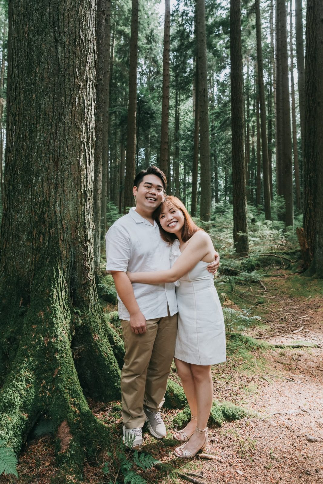 Richard and Mabel hugging beside a moss-covered tree in a sunlit forest